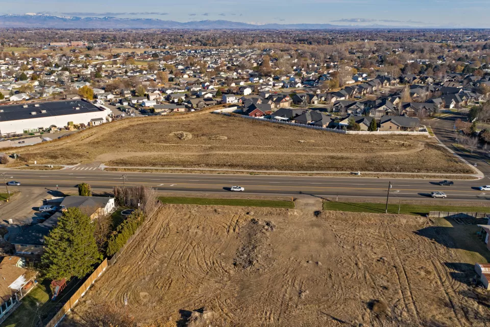 Aerial view of graded dirt lot ready for construction and houses with mountains in background near Boise, Idaho